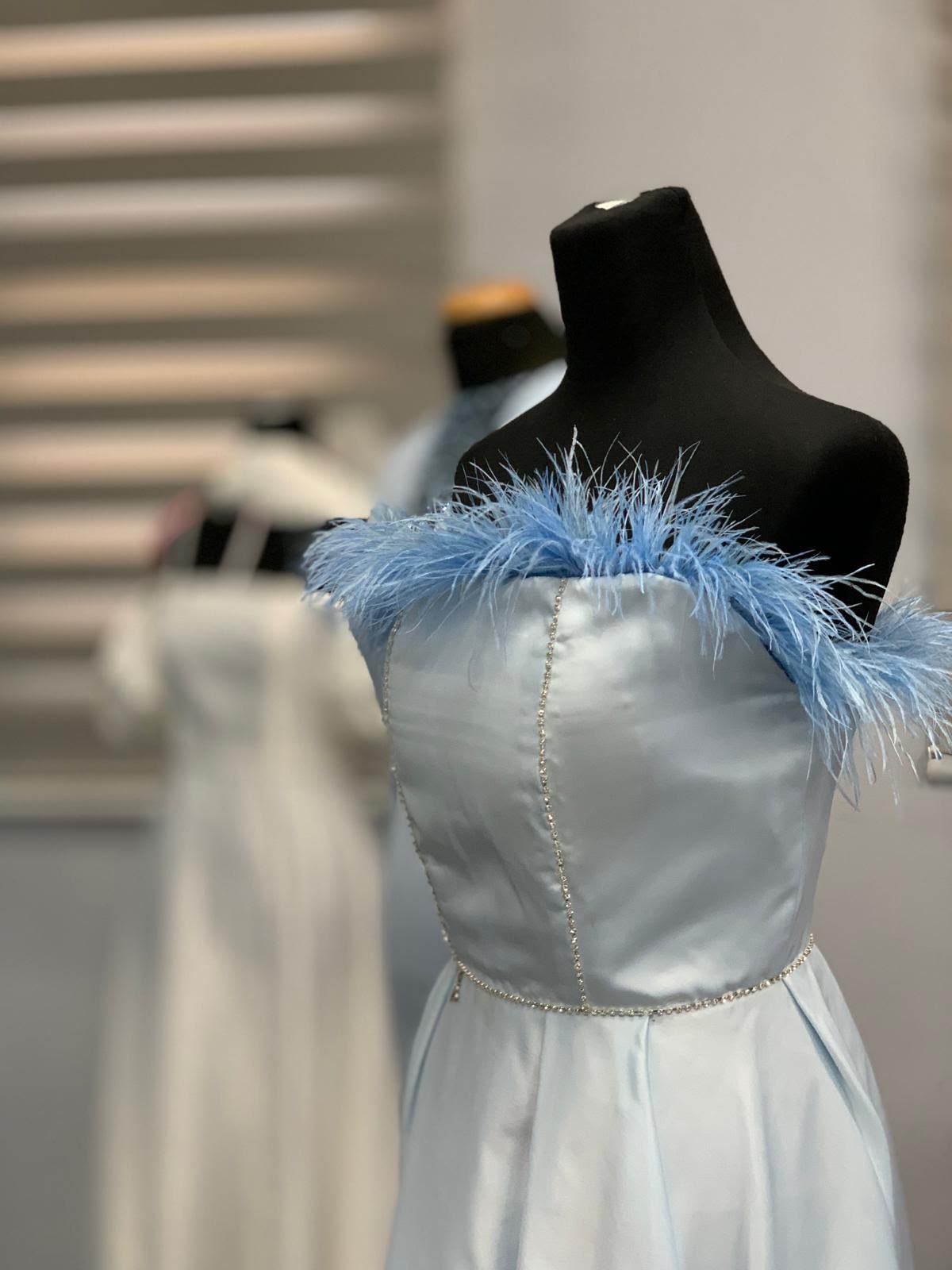 Light blue feathered satin dress on a mannequin